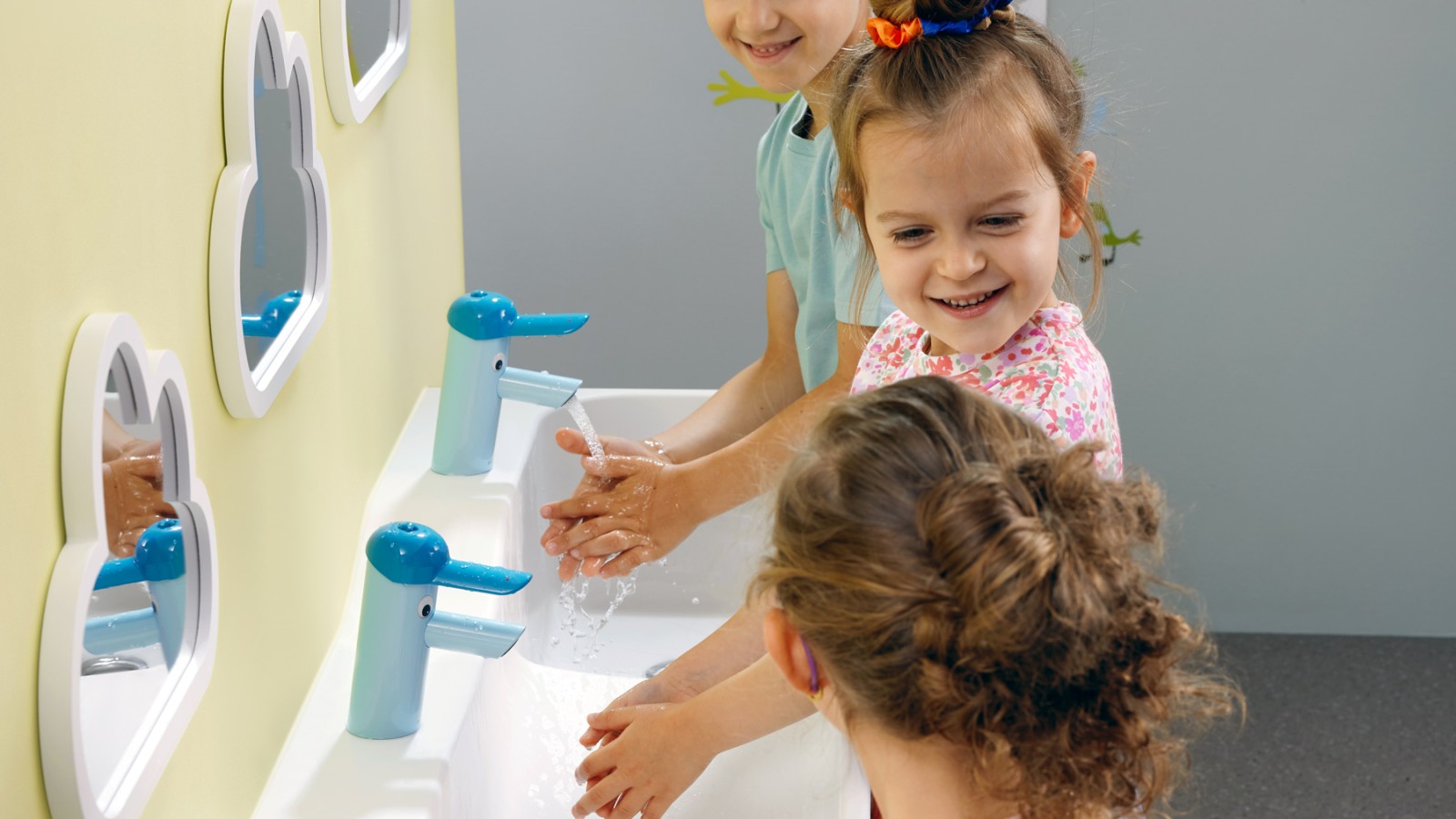 A gyerekek egy Geberit Bambini játszó- és mosakodóhelynél kezet mosnak A gyerekek egy Geberit Bambini játszó- és mosakodóhelynél kezet mosnak