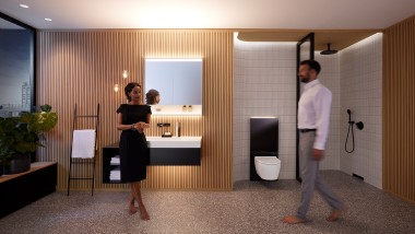 Egy férfi és egy nő egy Geberit ONE fürdőszobabútorokkal és kerámiákkal berendezett, harmonikusan megvilágított fürdőszobában (© Geberit)