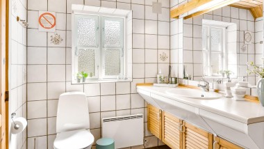 Az eredeti fürdőszoba álló WC-vel, fehér csempével és fából készült fürdőszobabútorokkal (© @triner2 és @strandparken3)