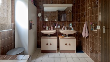 Fürdőszoba barna csempével és két mosdóval
