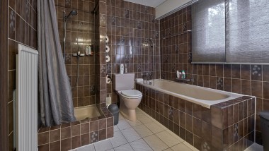 Fürdőszoba kis zuhanyzósarokkal, fürdőkáddal és álló WC-vel