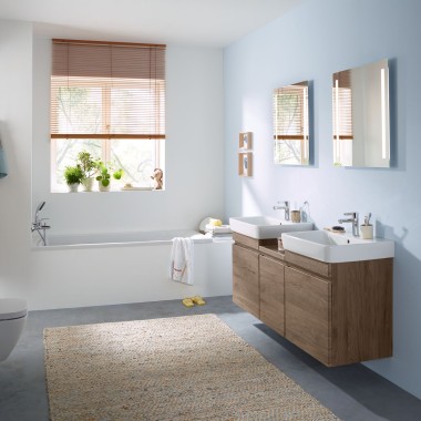 Családi fürdőszoba világoskék fallal és Geberit hikoridió színű fürdőszobabútorokkal, tükrös szekrénnyel, működtetőlappal és szaniterkerámiával
