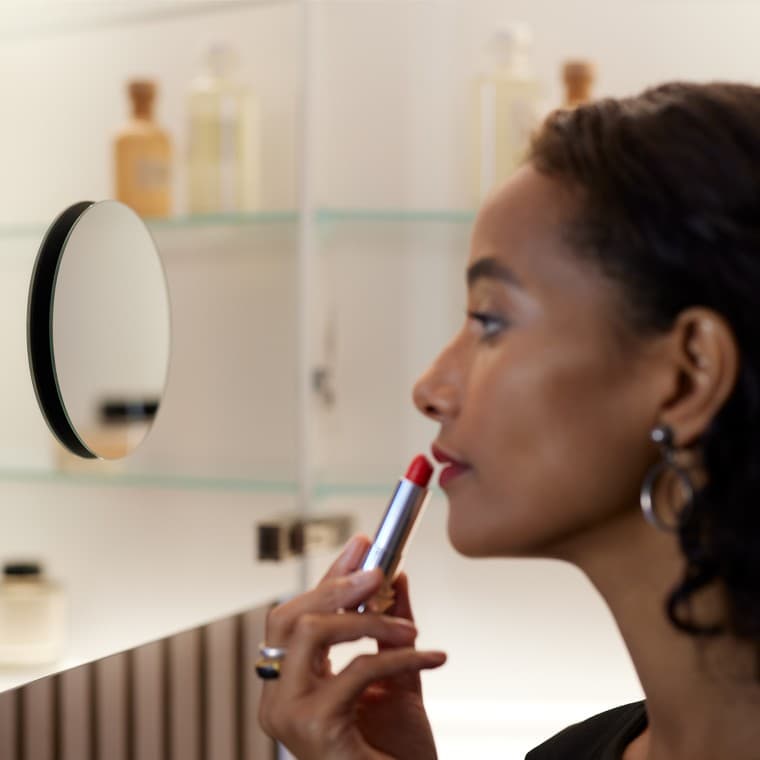 Egy nő a fürdőszobai tükörben sminkeli magát Egy nő a fürdőszobai tükörben sminkeli magát