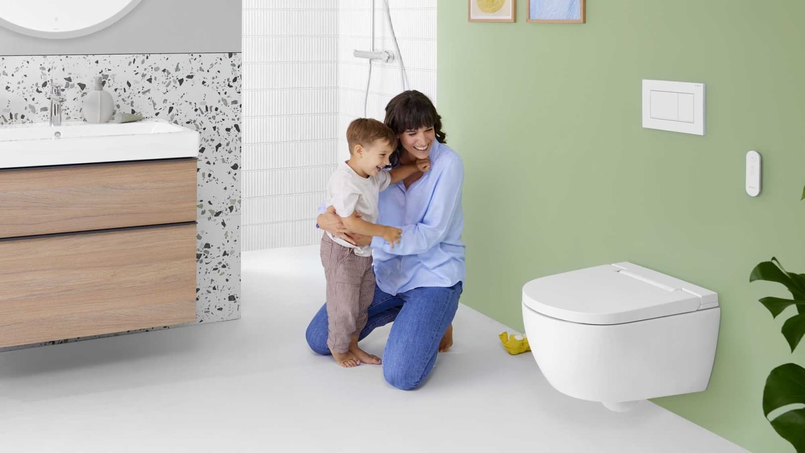 Nő gyermekkel egy Geberit AquaClean Alba higiéniai berendezés előtt Nő gyermekkel egy Geberit AquaClean Alba higiéniai berendezés előtt